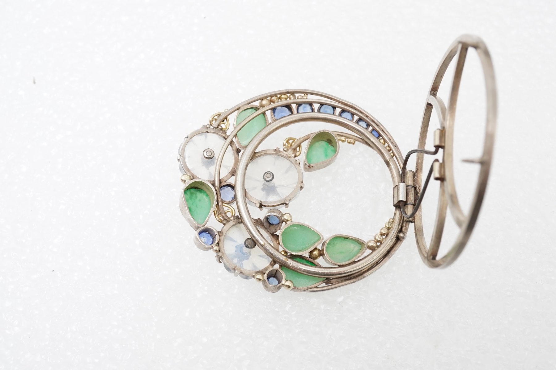 Attributed to Dorrie Nossiter (1893-1977), an Arts & Crafts moonstone, sapphire and jadeite scarf clip, 1920s